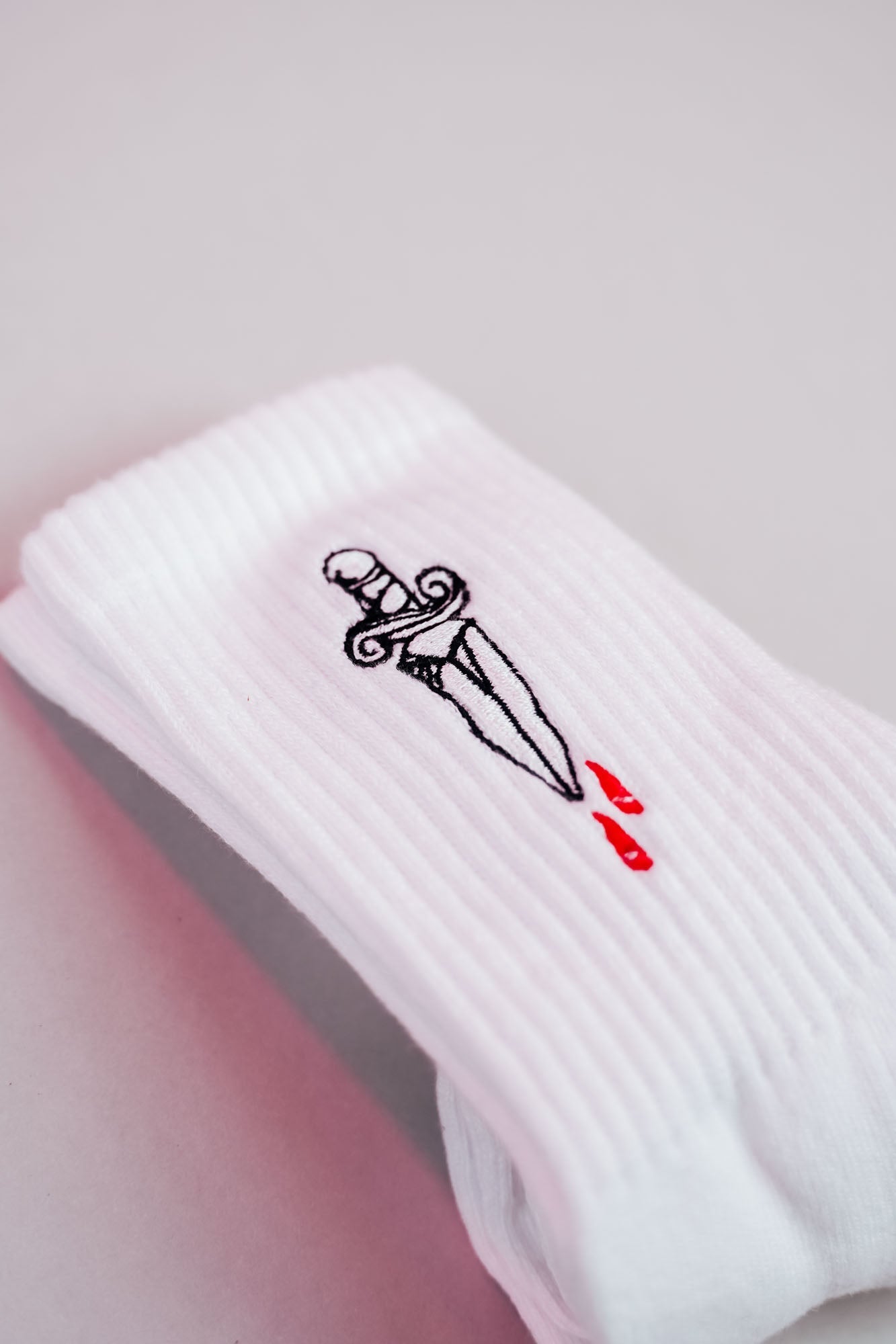 Weiße Socke mit kleinem gesticktem Dolchmotiv