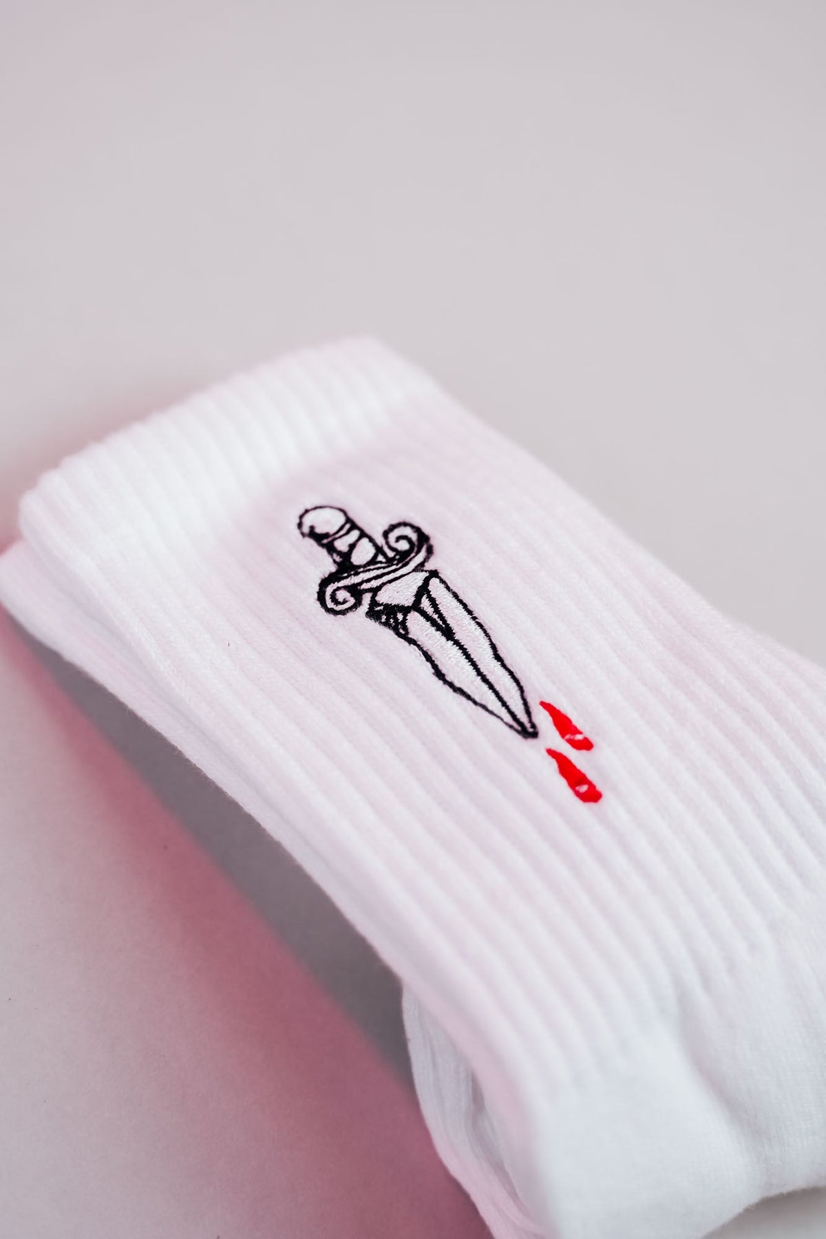 Weiße Socke mit kleinem gesticktem Dolchmotiv
