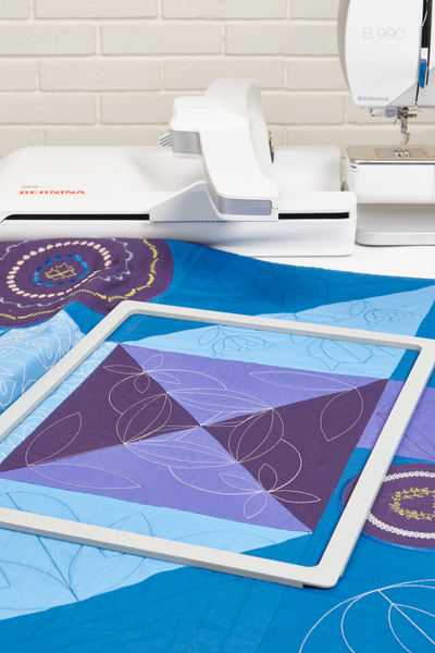 BERNINA Giant Magnet-Stickrahmen auf einem Quilt vor der BERNINA B 990 mit Stickmodul.