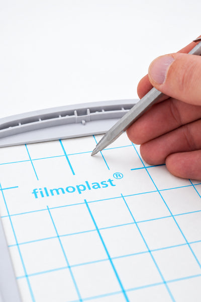 Gunold SLIT-PEN ridser beskyttelsespapiret på FILMOPLAST i en broderiramme