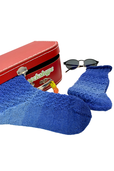 Blue 15-Years-Socks with a red travel case, sunglasses and boarding pass